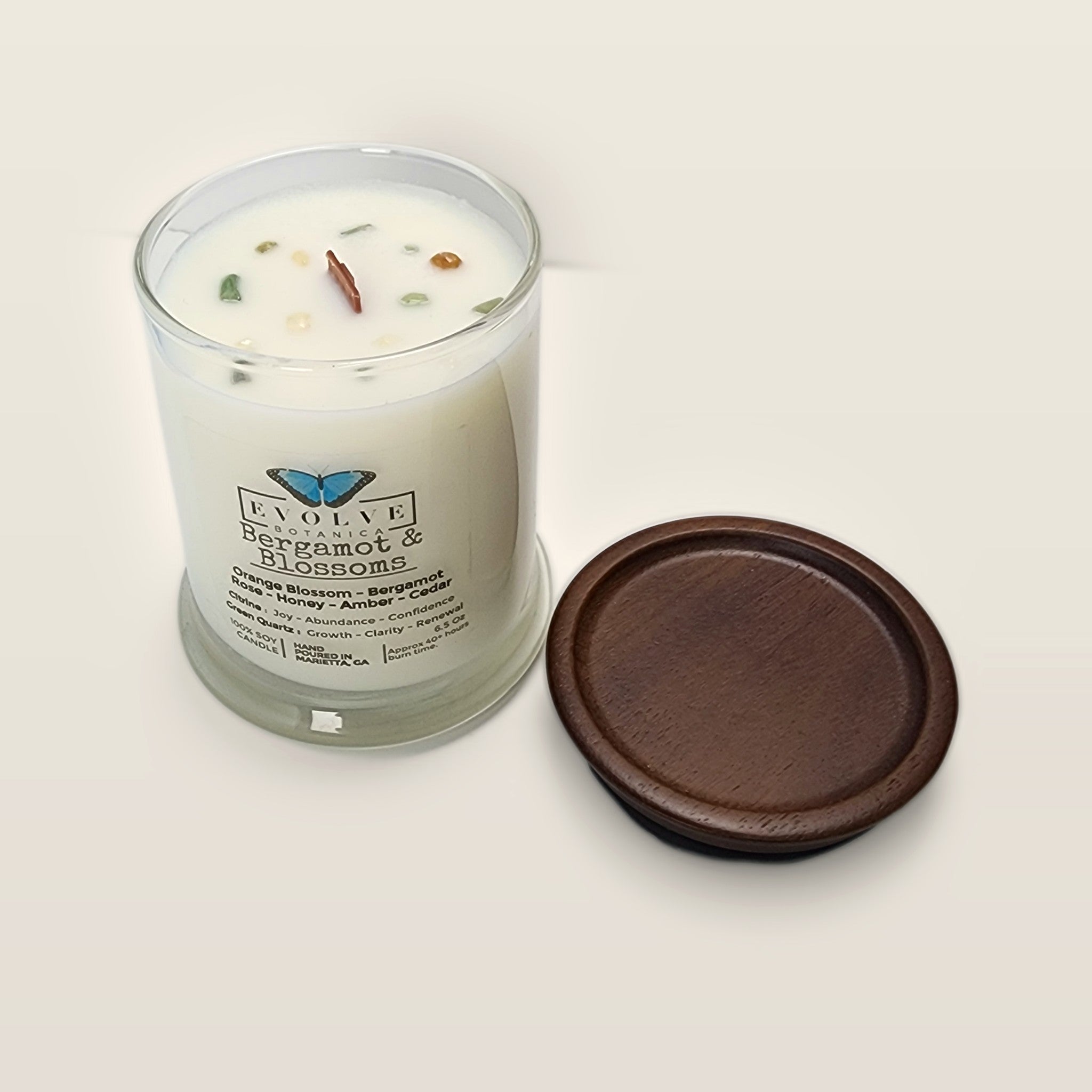 Evolve Botanica Bergamot & Blossoms 6.5 oz soy sipper candle angled view with wood wick and crystals