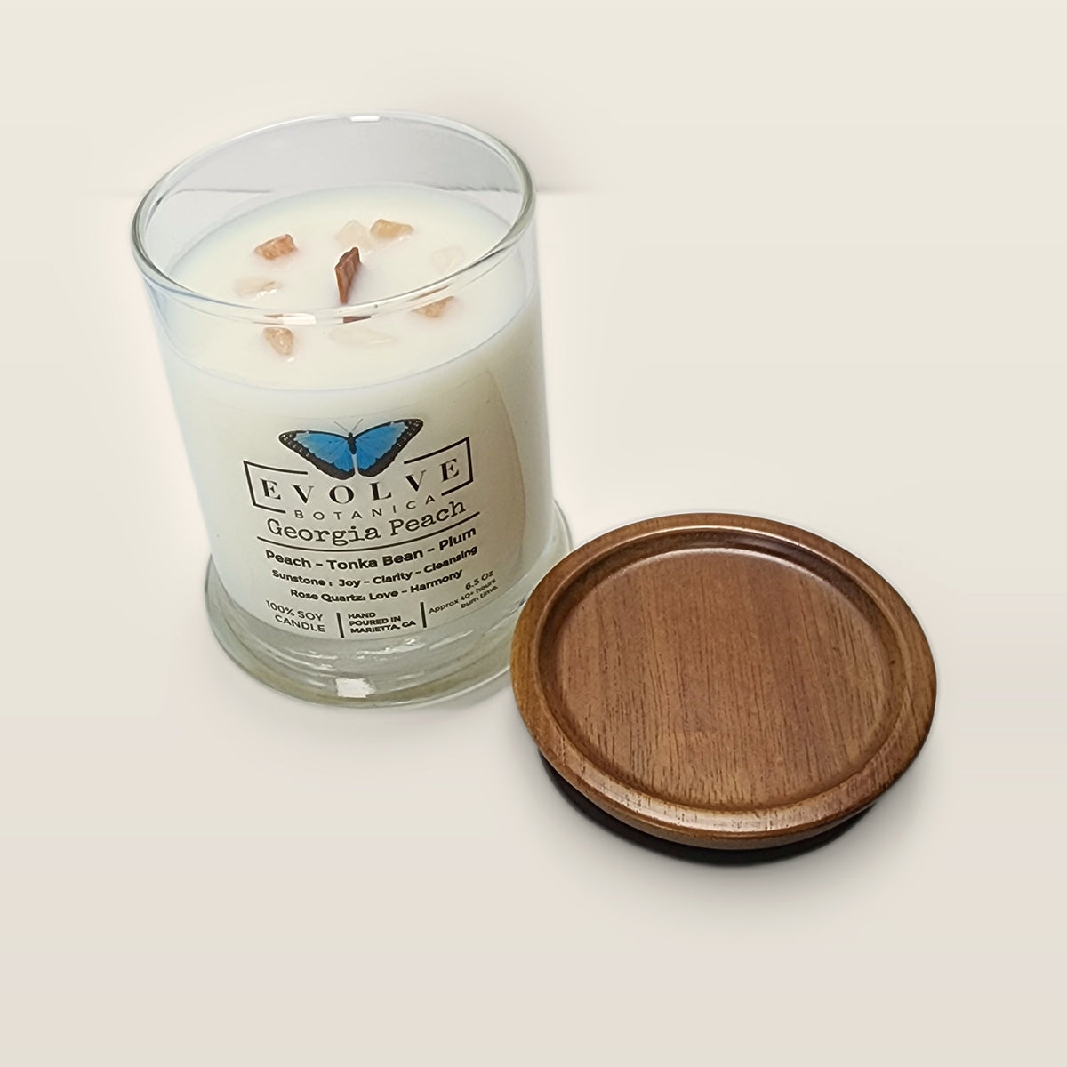 Evolve Botanica Georgia Peach 6.5 oz soy sipper candle angled view with wood wick and crystals