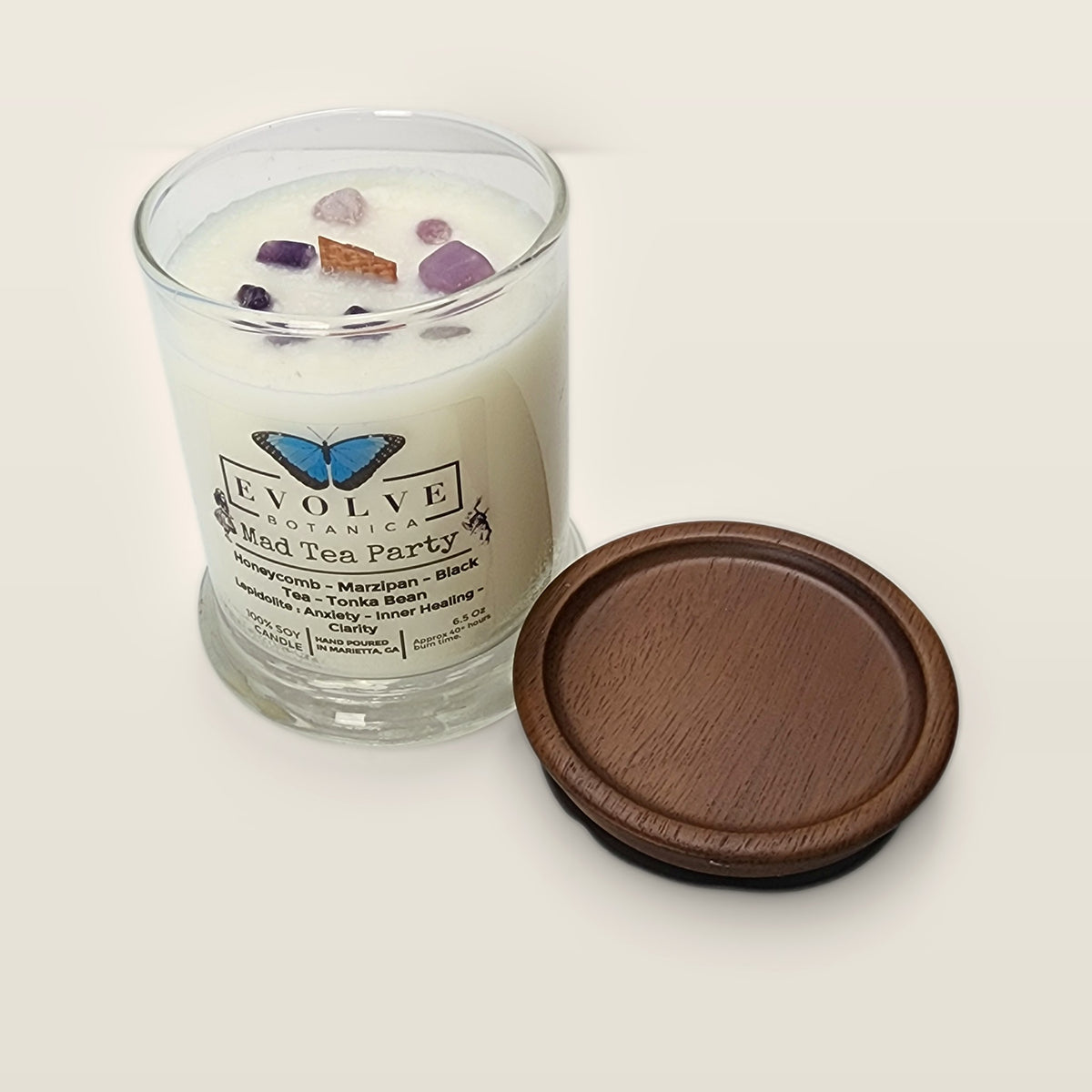 Evolve Botanica Mad Tea Party 6.5 oz soy sipper candle angled view with wood wick and crystals
