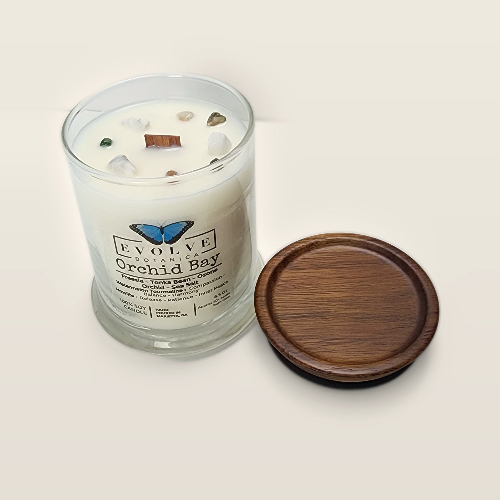Evolve Botanica Orchid Bay 6.5 oz soy sipper candle angled view with wood wick and crystals