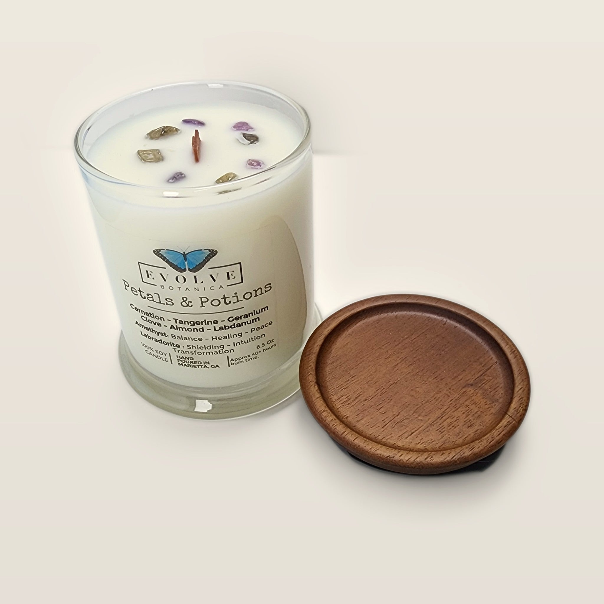 Evolve Botanica Petals & Potions 6.5 oz soy sipper candle angled view with wood wick and crystals