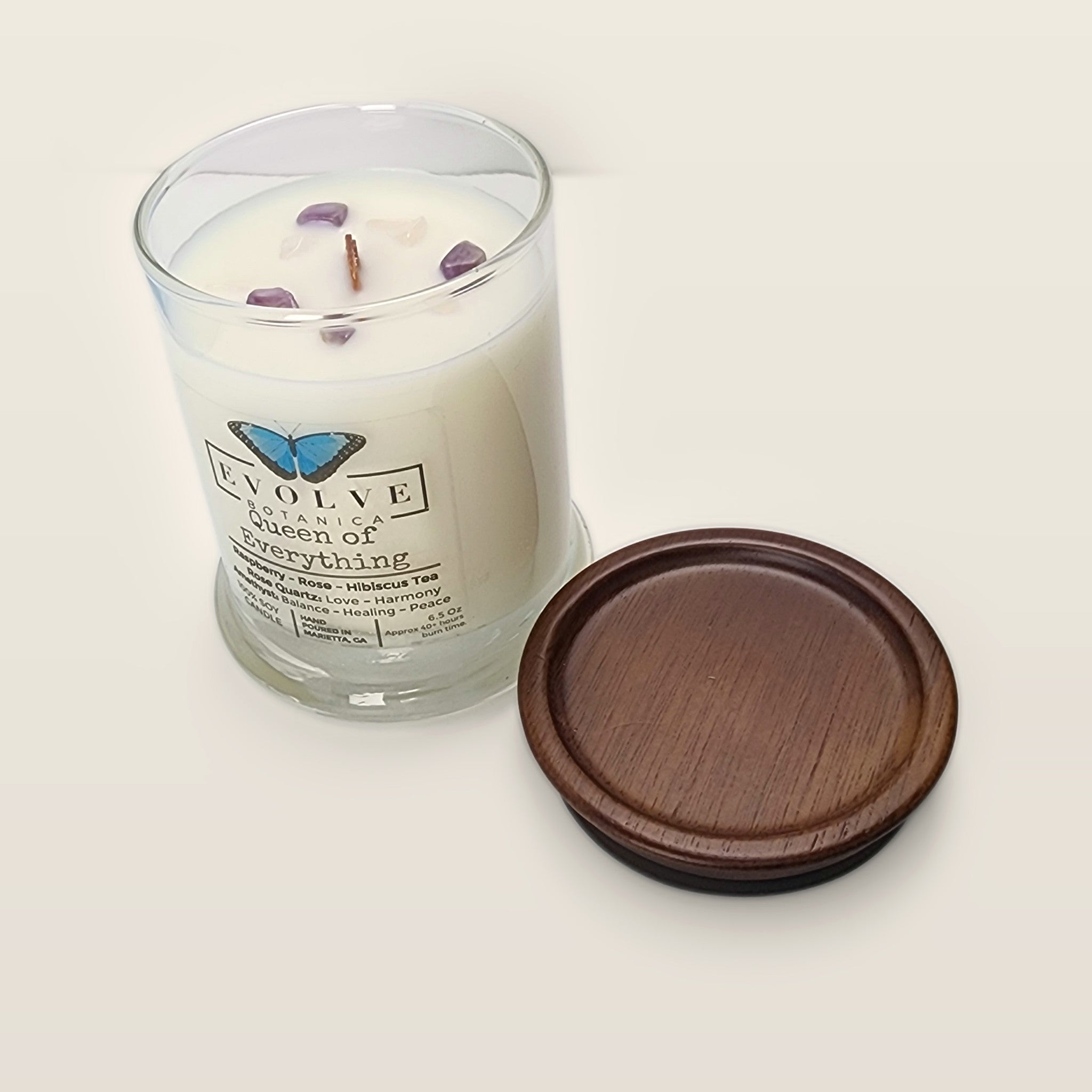 Evolve Botanica Queen of Everything 6.5 oz soy sipper candle angled view with wood wick and crystals