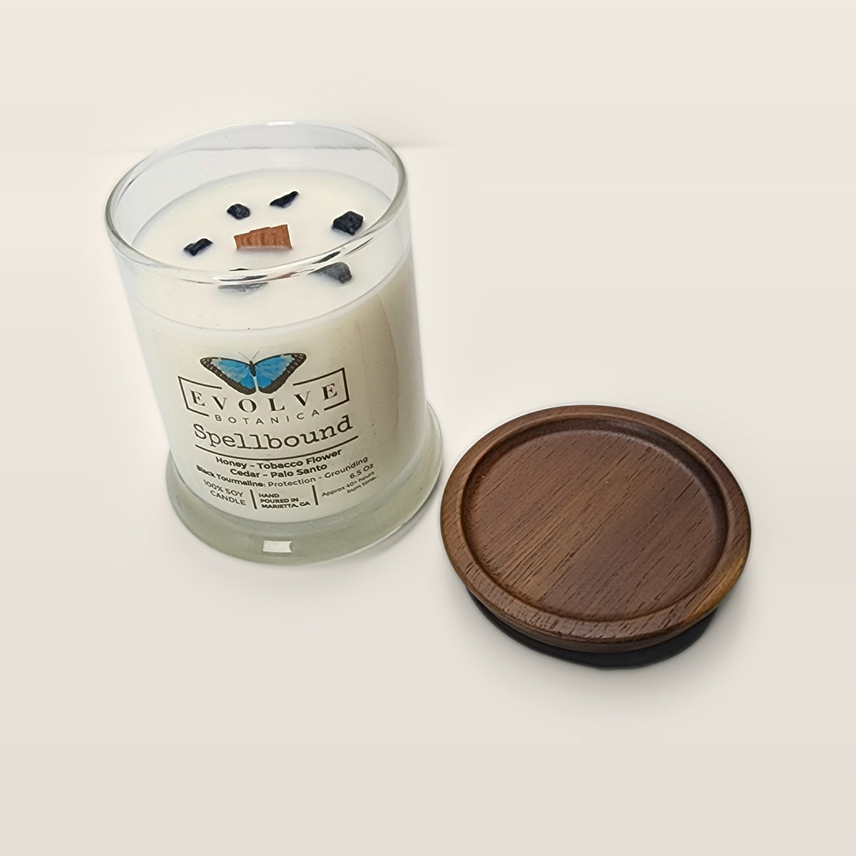 Evolve Botanica Spellbound 6.5 oz soy sipper candle angled view with wood wick and crystals