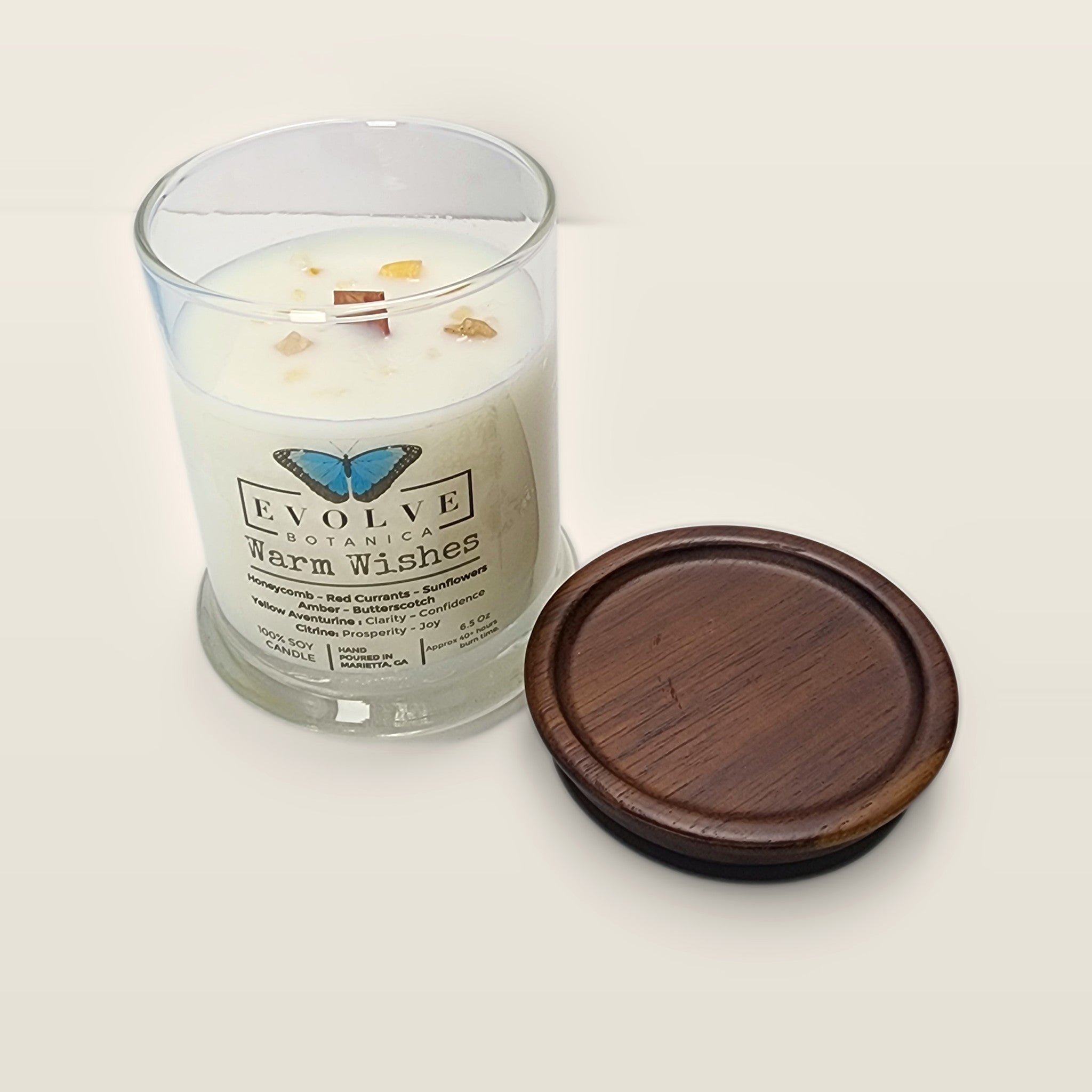 Evolve Botanica Warm Wishes 6.5 oz soy sipper candle angled view with wood wick and crystals
