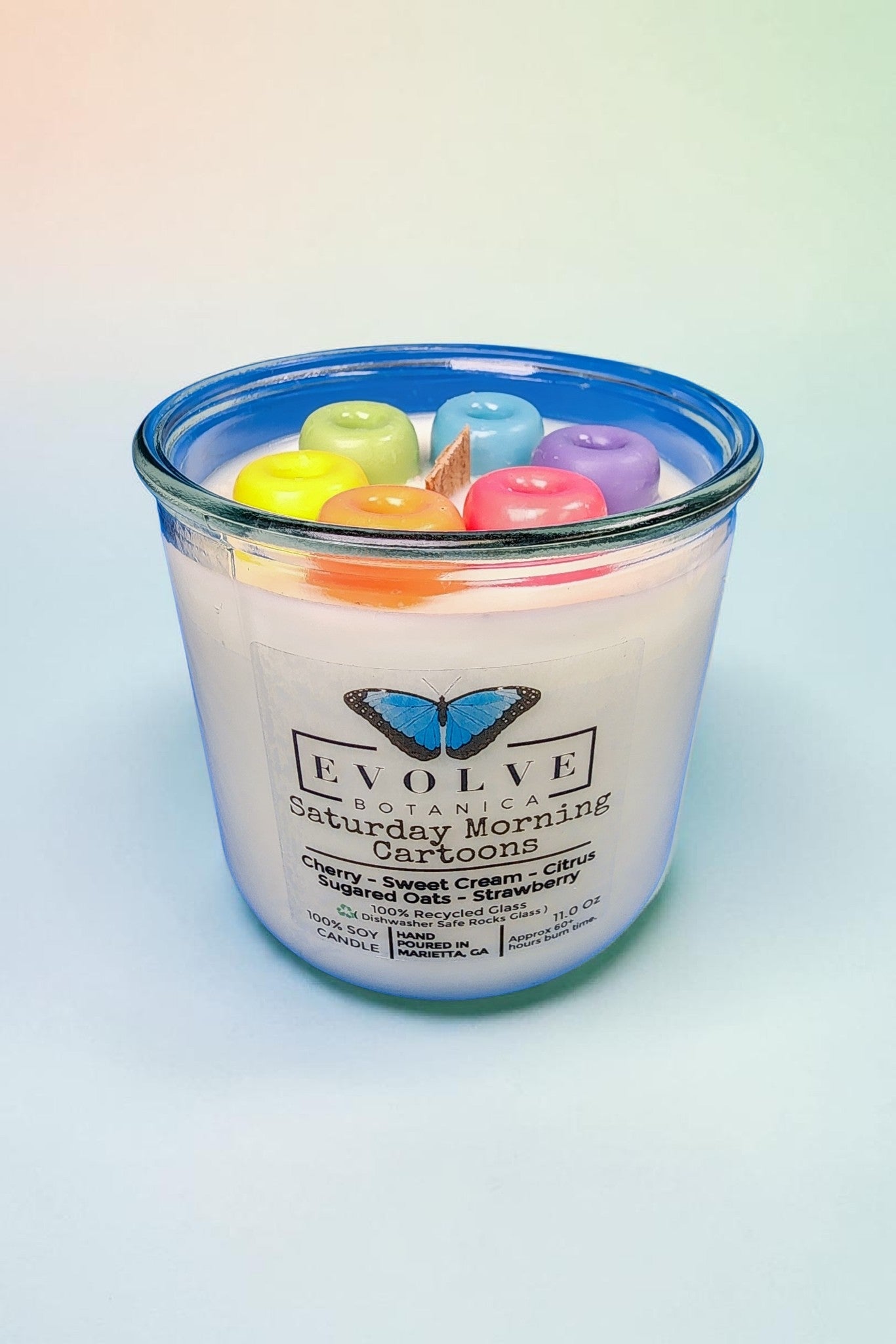 Close-up of handcrafted rainbow wax cereal loops on top of a hand-poured soy candle