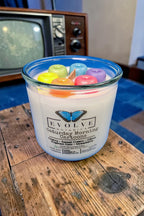 Candle with fruity cereal on a wooden surface with an old television in the background