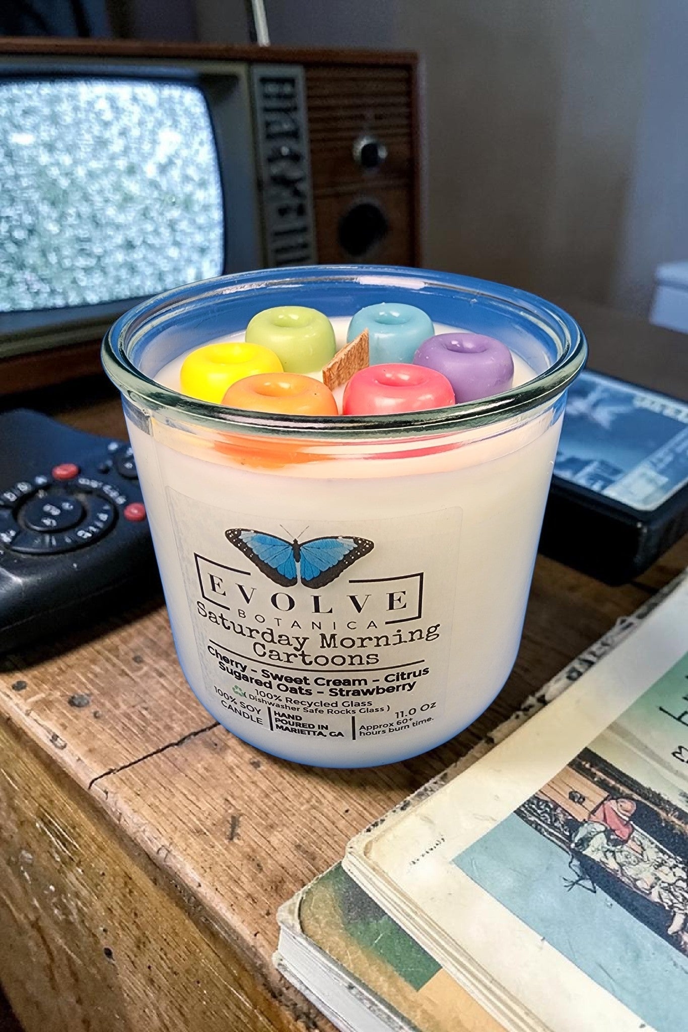 Candle with fruity cereal on a wooden surface with an old television in the background
