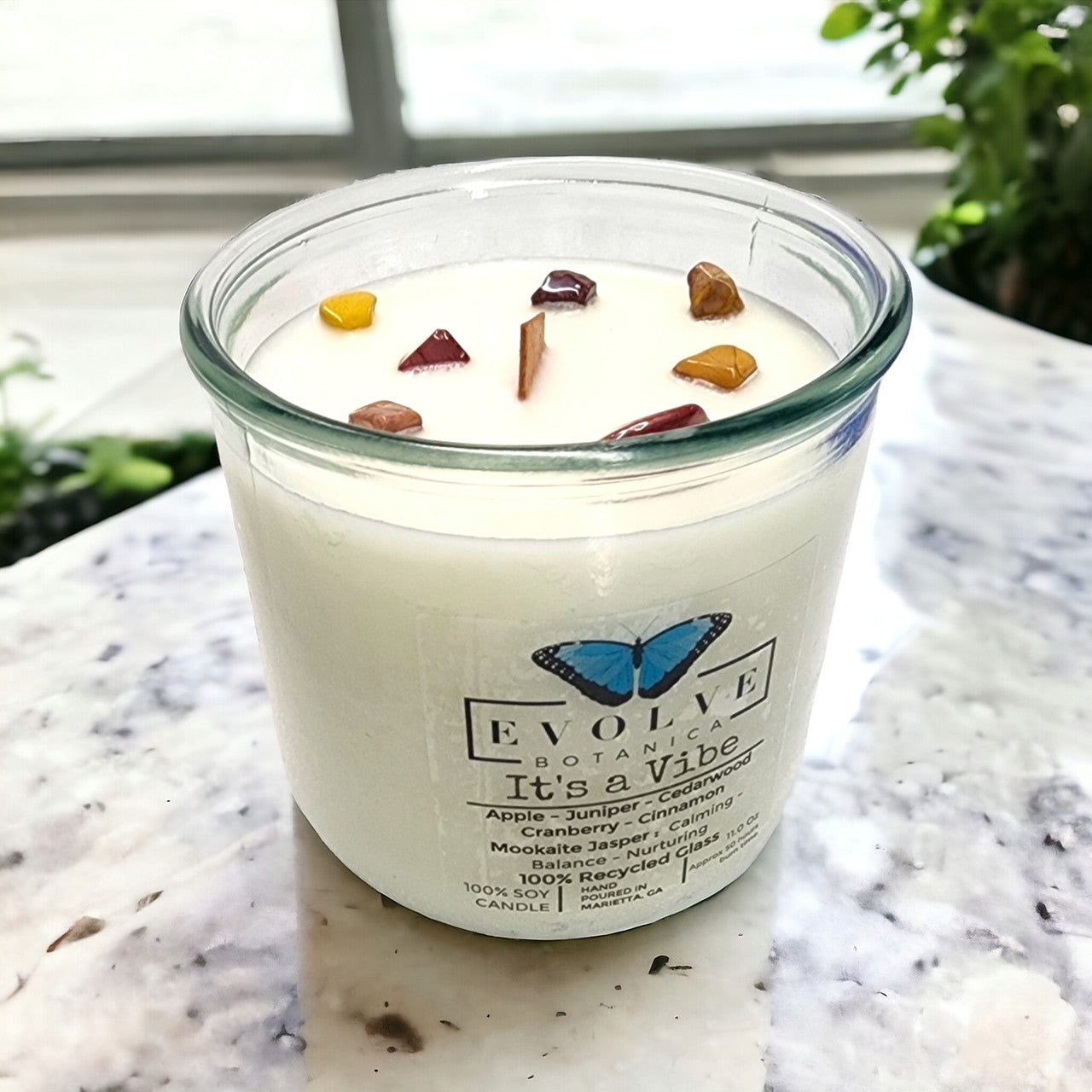 It's a Vibe Rocks candle side view showing Mookite Jasper crystal in soy wax