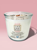 Evolve Botanica Hill Station Rocks Candle — wood wick soy candle topped with loose Hill Station chai (Chai Box × Evolve Botanica collab), scented with rose, cardamom and black tea