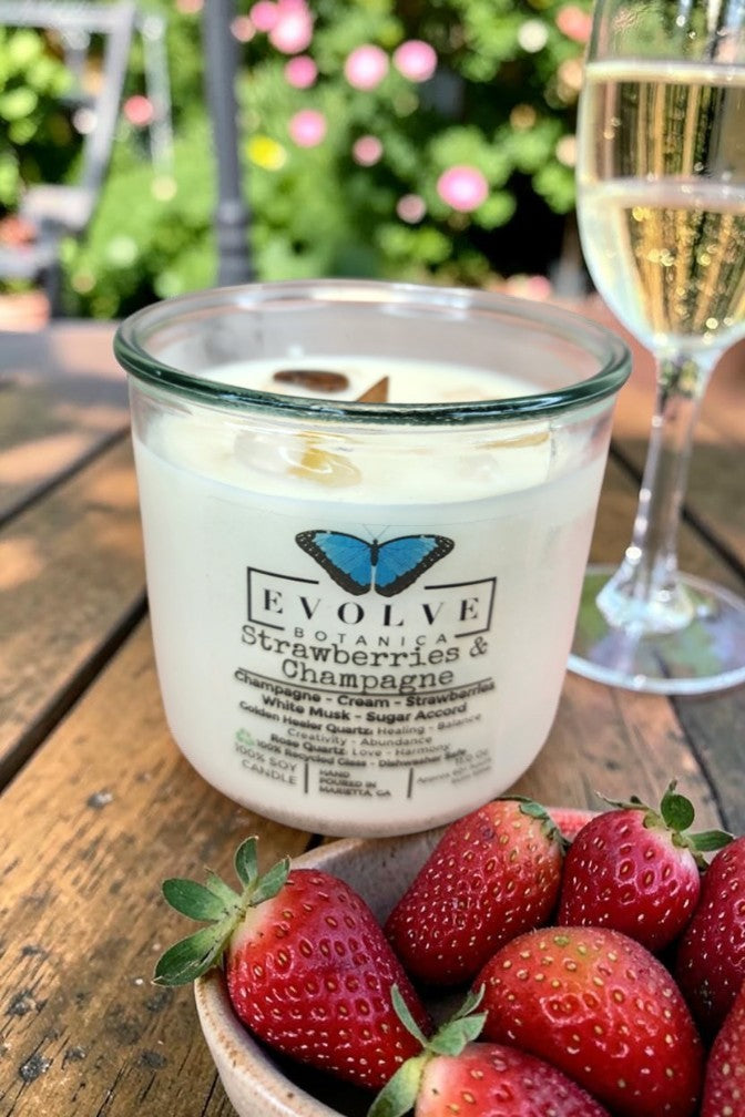 Strawberries & Champagne Rocks candle on a garden table with a champagne flute and fresh strawberries — champagne, cream and strawberry soy candle