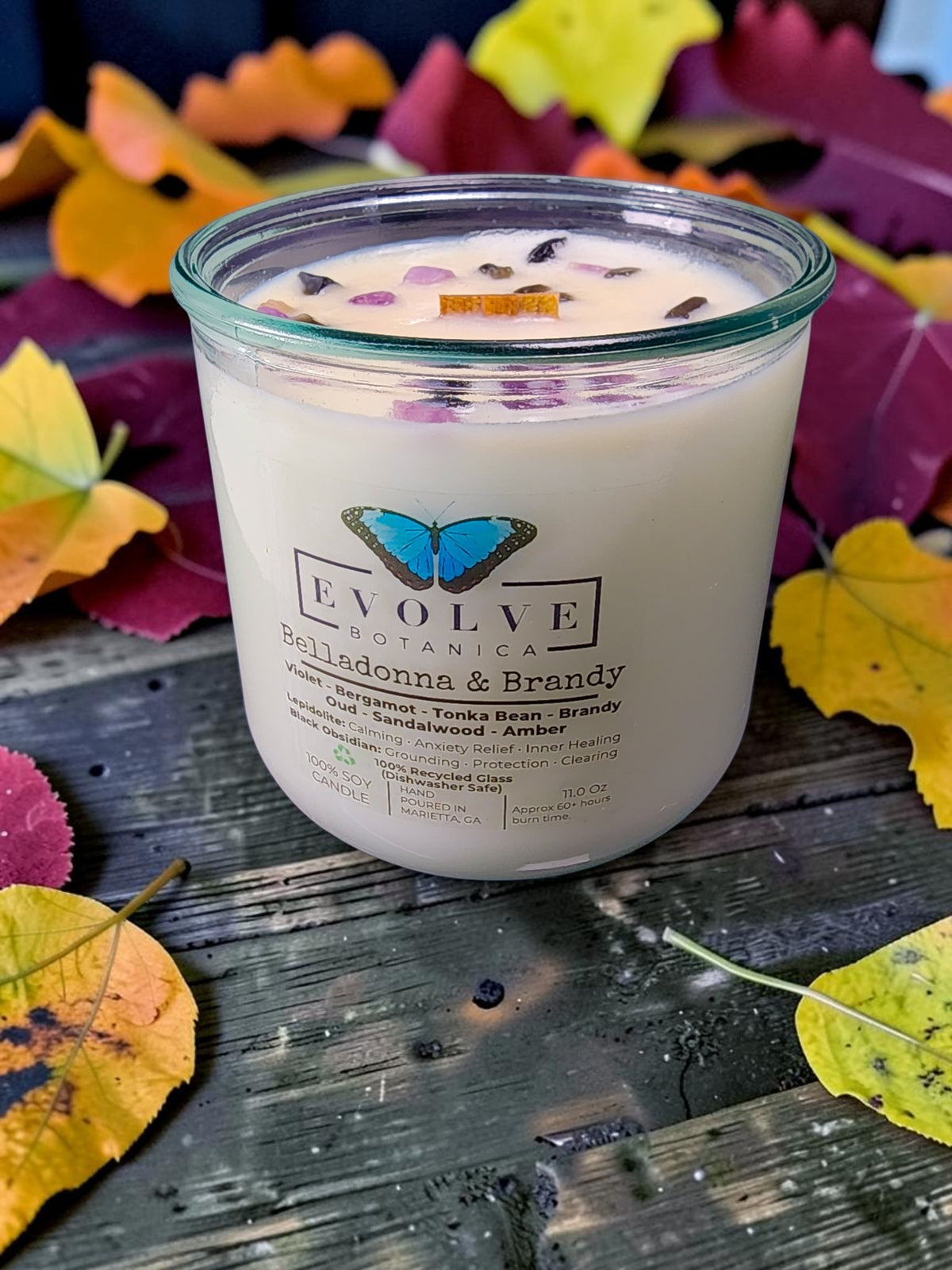 Belladonna and Brandy gemstone candle angled view on autumn leaves